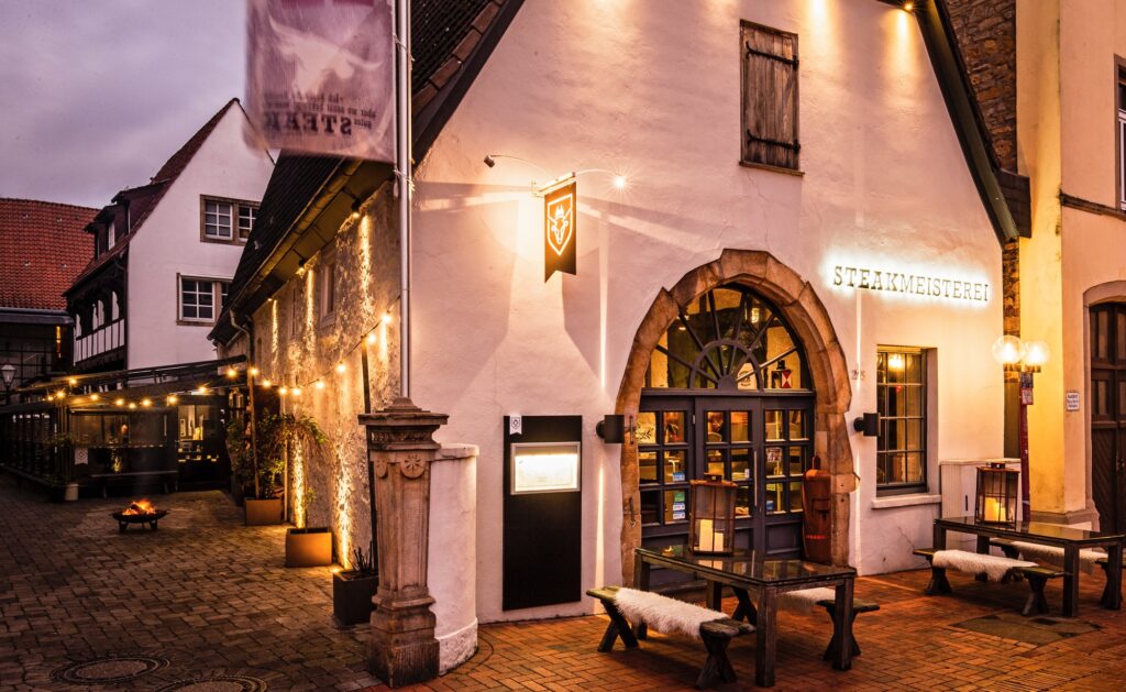 Die Steakmeisterei in Osnabrück am Abend, beleuchtete Fassade mit Rundbogen